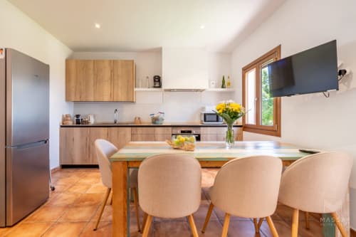 Cocina y comedor modernos en villa Can Jaumí, Artá, con muebles de madera, mesa de comedor y vistas al mar