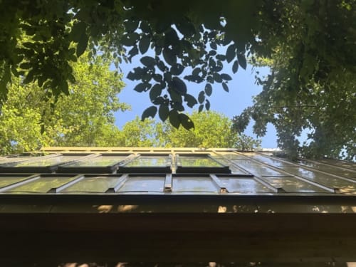 Plafond vitré offrant une vue sur le jardin et les arbres environnants de la chambre Prisma du gîte Micro Palaces à Vaulx, France