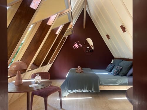 Chambre Prisma du Micro Palaces Vaulx avec plafond bois mansardé, lit queen-size, fauteuil violet et vue sur le jardin