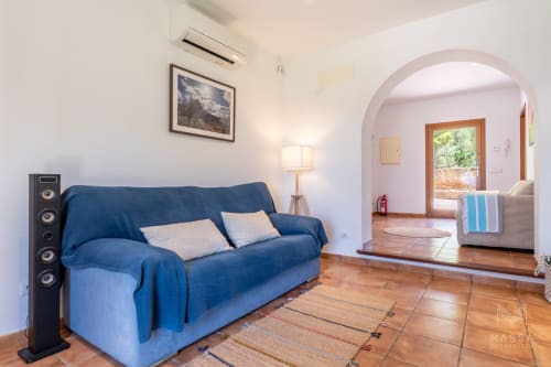 Sofá azul en sala luminosa con vistas al mar de la villa Can Jaumí, Artá, Mallorca