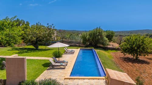 Villa de lujo Can Jaumí en Artá con piscina rectangular, tumbonas, sombrilla, jardines cuidados y vistas a la sierra, Alcúdia