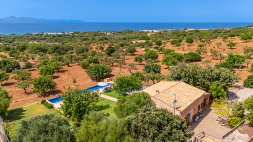 Vista aérea de Massa Properties en Artà: villa de terracota, piscinas azules, olivos y costa mediterránea.