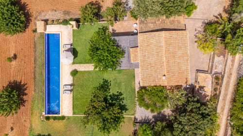 Vista aérea de villa vacacional Massa Properties en Artà con piscina azul, tejado de barro, jardines verdes y alrededores