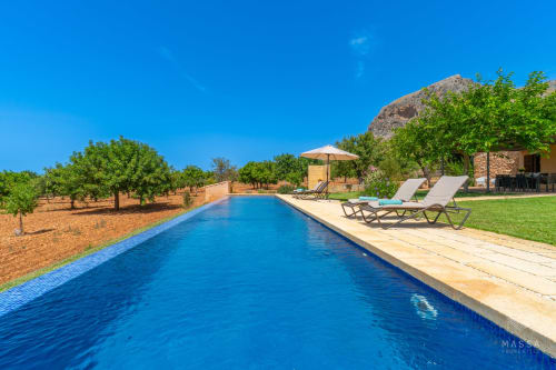 Piscina de lujo en Massa Properties, Artà, España con tumbonas, terraza de piedra y vistas a las montañas