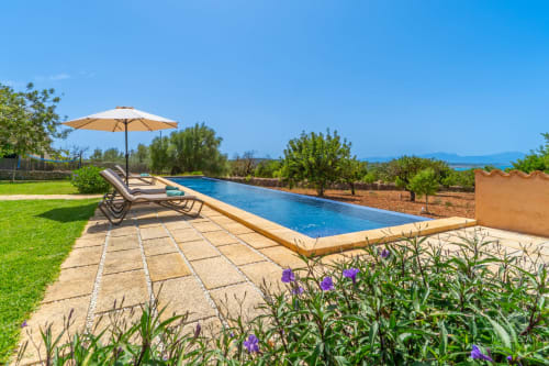 Villa de lujo con piscina en Artà, tumbonas, sombrilla, agua cristalina, jardines cuidados y vistas mediterráneas