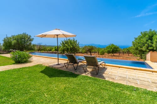 Área de piscina de lujo en Massa Properties Artà con tumbonas, sombrilla, vistas al mar y jardines cuidados