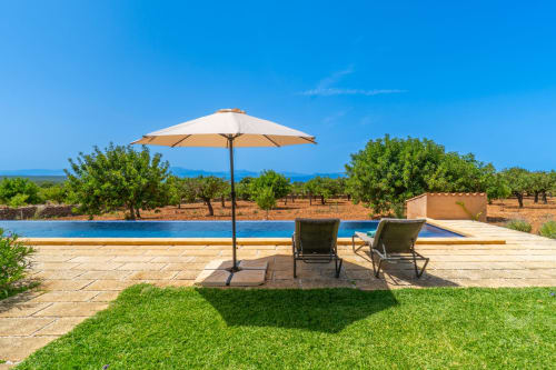 Área de piscina frente al mar en Massa Properties, Artà, con sombrilla, tumbonas y vistas al mar