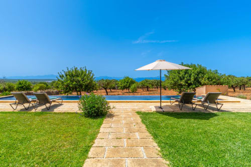 Piscina de Massa Properties en Artà con tumbonas, sombrilla, jardín impecable y vistas al Mediterráneo