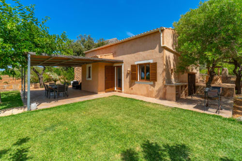 Villa mediterránea rústica en Artà con fachada de terracota, jardín cuidado, patio cubierto y olivos
