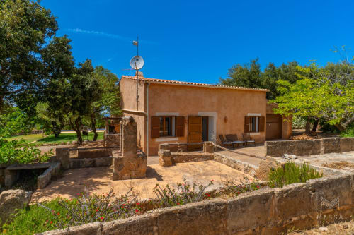 Villa rural Massa Properties en Artà con fachada de terracota, patio de piedra, antena parabólica y jardines mediterráneos