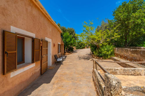 Villa de terracota rústica en Artà con contraventanas de madera, muros de piedra y exuberantes jardines mediterráneos