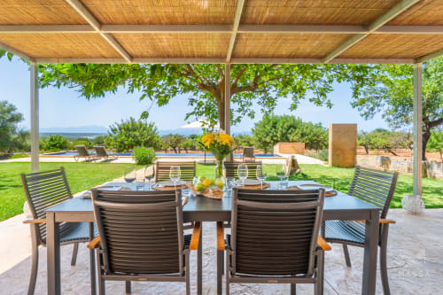 Terraza de comedor al aire libre en Massa Properties en Artà con vistas al mar, pérgola de madera y piscina