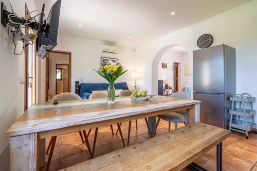 Cocina abierta moderna y sala de estar en Artà con mesa de comedor de madera, sofá azul y electrodomésticos de acero inoxidable