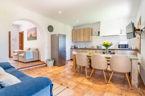 Cocina abierta y comedor en apartamento de Artà con muebles de madera, baldosas de barro y mobiliario moderno