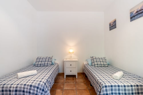 Habitación doble con ropa de cama de cuadros azules en el hotel Massa Properties de Artà, España