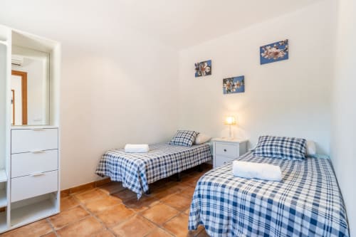 Dormitorio doble con ropa de cama a cuadros azules en Massa Properties, Artà, España