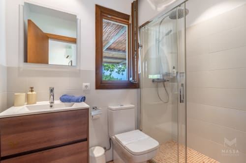 Cuarto de baño moderno en Massa Properties en Artà con vanidorio de madera, ducha de cristal, azulejos blancos y vista por la ventana