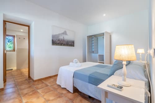 Moderno dormitorio de hotel en Artà con ropa de cama azul, baño privado, suelo de terracota y decoración contemporánea