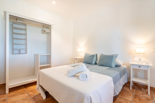 Luminoso dormitorio en el hotel Massa Properties de Artà con cama, baño privado, mesillas blancas y suelos de madera