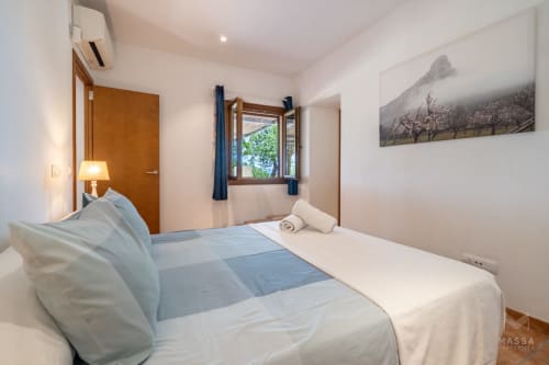 Dormitorio moderno en Massa Properties en Artà con cama confortable, puertas de madera y cuadros de paisaje montañoso