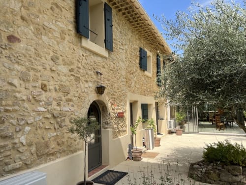 Cour de la Bastide des Princes à Caderousse : bâtisse en pierre, portail voûté, olivier et terrasse