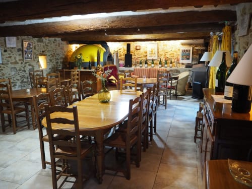 Salle à manger rustique à La Bastide des Princes avec poutres apparentes, tables et cave à vin à Caderousse