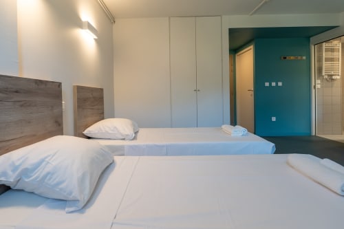 Lits jumeaux aux draps blancs dans la chambre lumineuse de la Maison Du Haut Salat, Seix, France