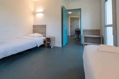 Chambre moderne à la Maison Du Haut Salat à Seix avec deux lits, têtes de lit en bois et porte turquoise
