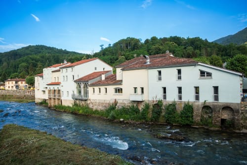 Hôtel Maison Du Haut Salat à Seix, France : bâtiments blancs au bord d'une rivière animée, entourés de montagnes verdoyantes