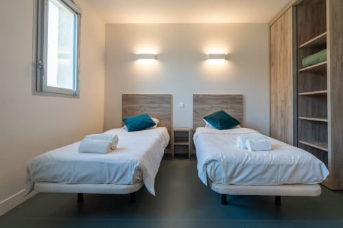 Chambre double à la Maison Du Haut Salat à Seix avec deux lits, oreillers bleu-vert, têtes de lit en bois et rangements