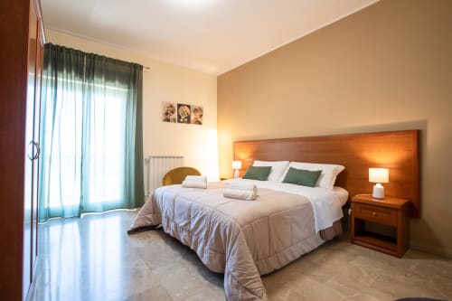 Ampia Suite Familiare presso La Zagara Rooms a Milazzo con vista sul mare, letto in legno, cuscini verdi e luminosa