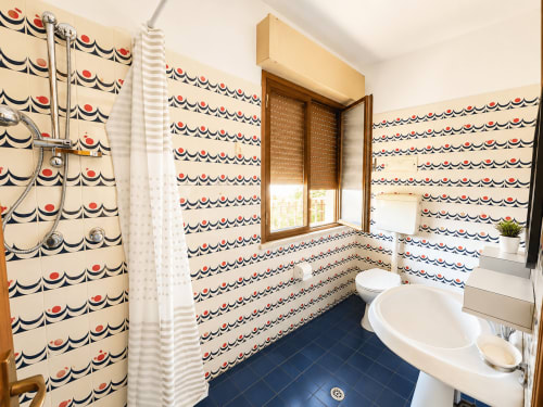 Bagno retrò colorato con piastrelle blu e carta da parati decorata all'hotel Anthea, Lignano Sabbiadoro
