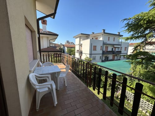 Balcone con tavolo da pranzo dell'Anthea Hotel Villa Loris 3, Lignano Sabbiadoro, con vista sul giardino e il campo da tennis