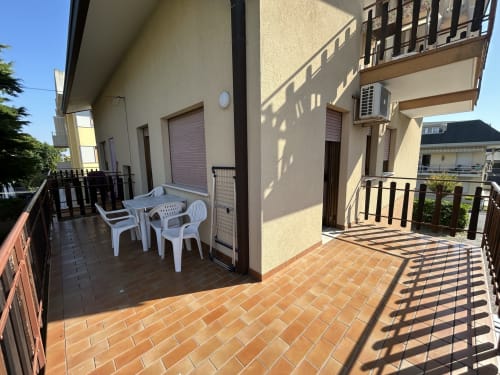 Terrazza soleggiata di Villa Loris 3, Anthea Hotel Lignano Sabbiadoro, con sedie bianche e vista sul giardino