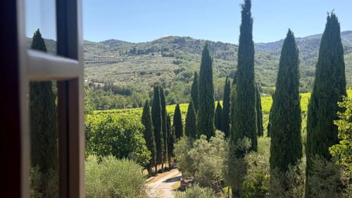 Tuscany villa view with cypress trees, rolling hills, and vineyard landscape at Borgo di Erboli, Cavriglia