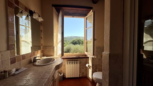 Bathroom in Borgo di Erboli apartment, Cavriglia, with terracotta tiles, sink, toilet, and open window overlooking Tuscan