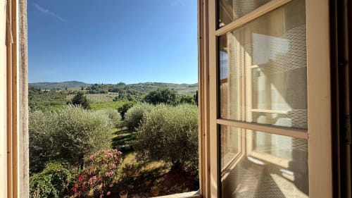 Open window view of Tuscan olive groves and rolling hills at Borgo di Erboli, Cavriglia