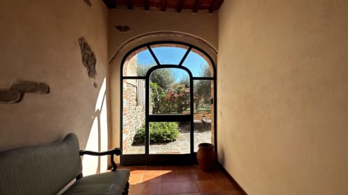 Arched doorway at Borgo di Erboli in Cavriglia, Italy, opening to a garden courtyard with terracotta floors