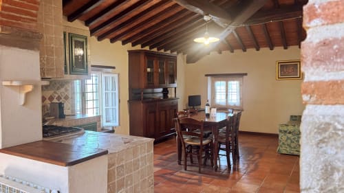 Family apartment at Borgo di Erboli in Cavriglia with kitchen, dining area, wooden beams, and terracotta tile floors
