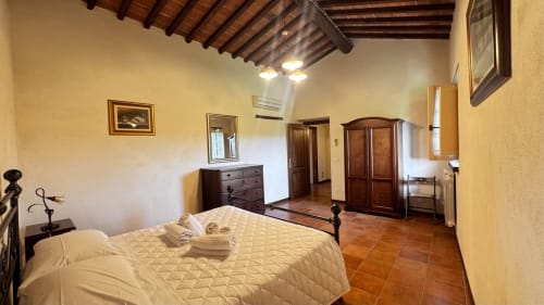 Spacious bedroom in Borgo di Erboli family apartment, Cavriglia, with terracotta floors and wooden beamed ceiling