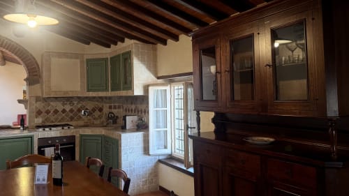 Rustic Italian kitchen with green cabinetry, exposed beams, and wooden furniture at Borgo di Erboli in Cavriglia