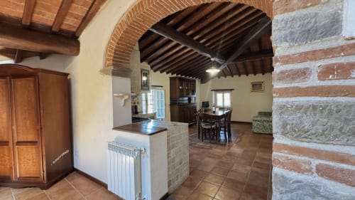 Rustic apartment kitchen and dining area at Borgo di Erboli with exposed wooden beams, arched brick ceilings, and traditional
