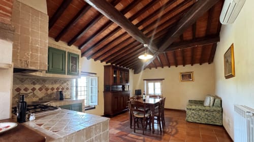 Family apartment at Borgo di Erboli in Cavriglia with exposed wooden beams, kitchen, dining area, and terracotta floors