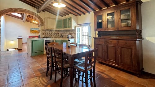 Tuscan apartment kitchen and dining area at Borgo di Erboli with wooden beams, green cabinetry, and rustic furnishings
