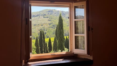 Open window at Borgo di Erboli with view of Tuscan cypress trees and green hillside landscape near Cavriglia