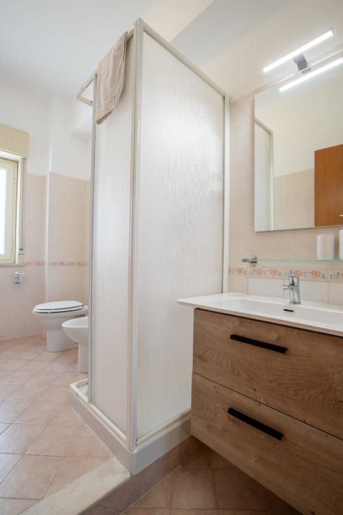Bagno moderno con mobile a legno, doccia e toilette presso La Zagara Rooms a Milazzo