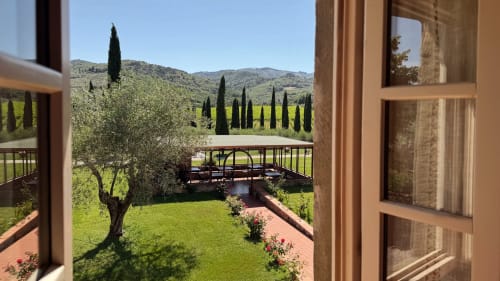 Tuscan countryside view from Borgo di Erboli apartment with cypress trees, olive groves, and garden bridge in Cavriglia,