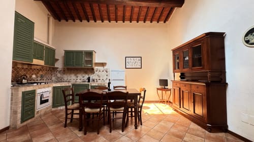 Family apartment kitchen and dining area at Borgo di Erboli, Cavriglia, with green cabinets and rustic wooden furniture