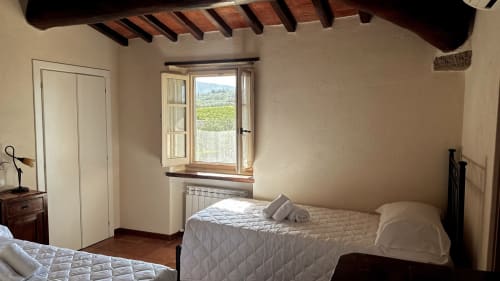 Rustic bedroom at Borgo di Erboli, Cavriglia with exposed beams, twin beds, and countryside view
