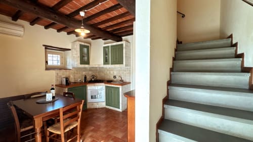 Borgo di Erboli Family Apartment in Cavriglia features rustic kitchen with green cabinets and stairs